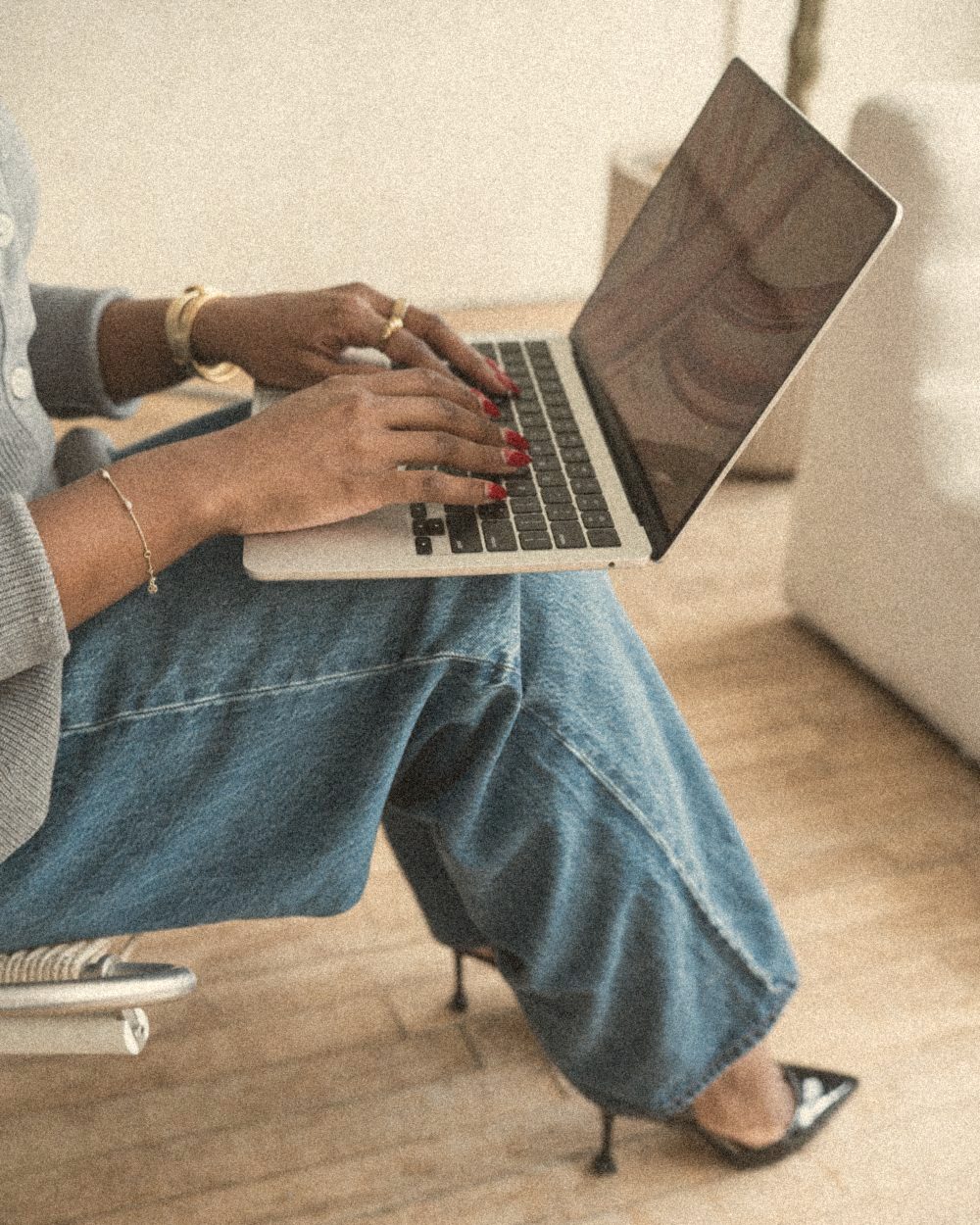 Hands typing on a laptop in a sunlit studio